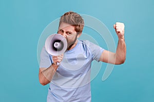 Man holding megaphone near mouth, loudly speaking, screaming, making announcement with raised arm.