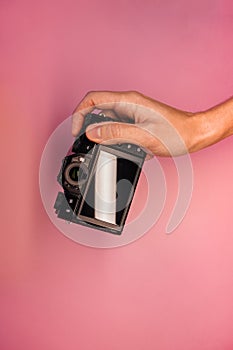 A man holding a mirrorless camera in his hands on a light background top view. photographer adjusts the camera close-up.