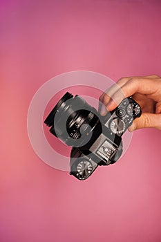 A man holding a mirrorless camera in his hands on a light background top view. photographer adjusts the camera close-up.