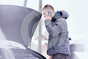 Man holding mobile phone and calling winter car services to help