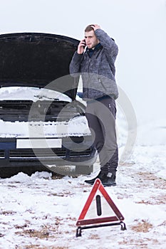 Man holding mobile phone and calling winter car services to help