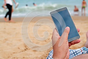 Man holding a mobile phone. Internet connection on the beach