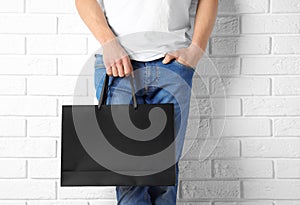 Man holding mock-up of paper shopping bag