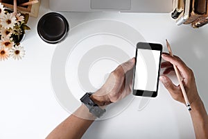 Man holding mockup smartphone on office desk.