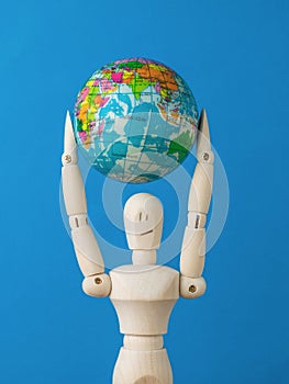 A man holding a model of the globe above his head on a blue background. Earth Day