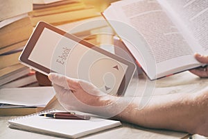 Man holding a modern ebook reader and book in library