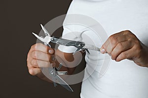 Man holding multitool on dark background, closeup