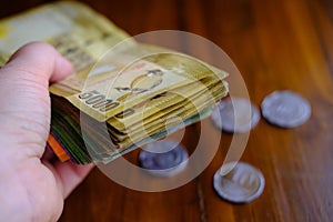 man holding national currency of Sri Lanka, paper money bills Rupee banknotes, coins on table, devaluation, high inflation of