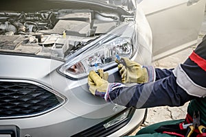 Man holding new lamps near car headlamps