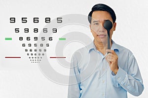 Man holding ocluder with eye vision examination chart