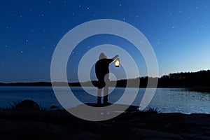 Man holding the old lamp outdoors near the lake. Hand holds a large lamp in the dark.