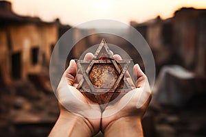 A man holding an old and rusty star of David in their hands on ruins background.