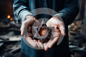 A man holding an old and rusty star of David in their hands on ruins background.