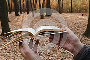 Man holding open book in forest