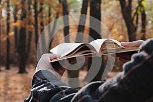 Man holding open book in forest