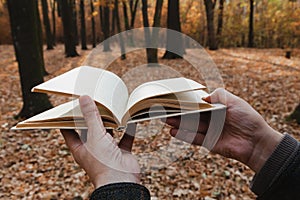 Man holding open book in forest