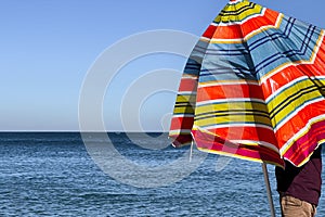 A man holding an open parasol on the beach