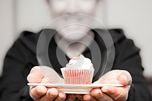 Man holding out a pink cupcake to his sweetheart