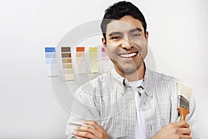Man Holding Paintbrush In Front Of Color Samples