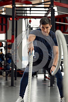 Man holding a pair of battle ropes for workout. guy at the gym working out with fitness rope.