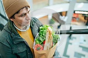 Man Holding Paper Bag Full of Food