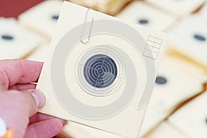 Man holding a paper target at a shooting range with a hole.