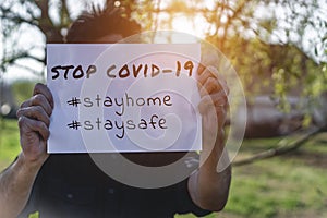 Man holding a paper with text and strong message Stop Covid-19 corona virus.