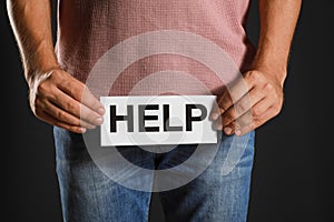 Man holding paper with word HELP on black background, closeup