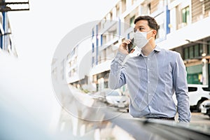 A man is holding a phone outside, wearing a face shield to protect against germs and viruses. Dust prevention and prevention of