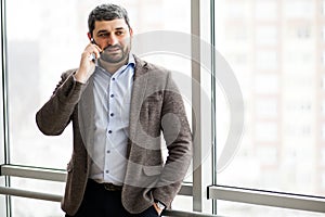 Man holding phone - young businessman using smartphone in office