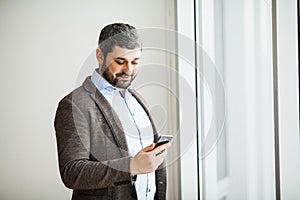 Man holding phone - young businessman using smartphone in office