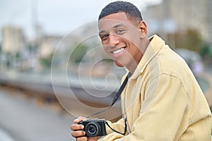 Man holding photo camera looking at camera outdoors