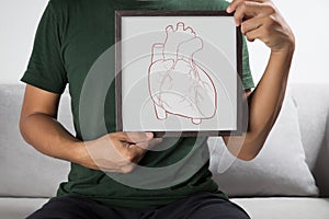 A man holding a photo frame with heart outlines photo