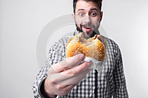 Man holding a piece of hamburger. student eats fast food. not helpful food. very hungry guy