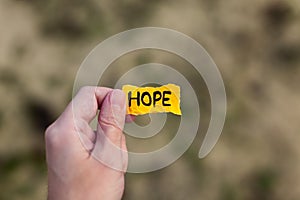 Man holding piece of yellow paper with the word Hope in his hand