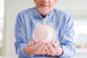 Man holding piggy bank carefully and smiling, saving money for retirement