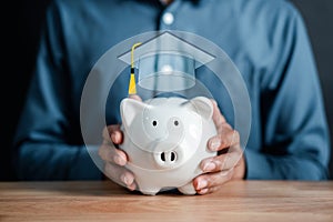 Man holding piggy bank with graduation cap. saving money for future education. Education fees and cost of college graduate.