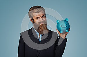 Man holding piggy bank money box over blue