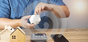 Man holding a piggy bank on a wooden table, money saving planning, business, finance, payment guidelines, financial concept