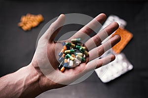 Man holding a pills. Medicine on a black background. HandÂ´s of young man holding a tablets, pills.