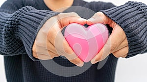 Man holding a pink heart on a white background