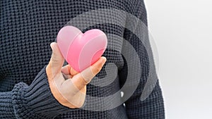 Man holding a pink heart on a white background