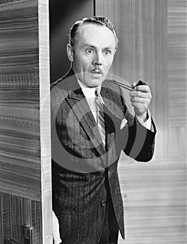 Man holding a pipe and standing at a doorway looking very surprised