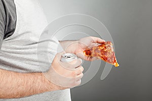 Man holding pizza slice and canned beverage