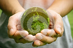 man holding planet in hands against green spring background. Earth day concept.