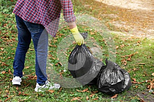 Man holding plastic bags with garbage in park, closeup