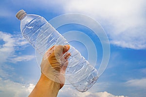 Man holding a plastic bottle of water.Backdrop sky