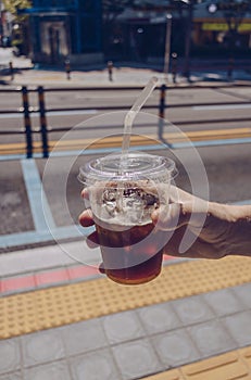 Man holding plastic mug of iced convinience store coffee