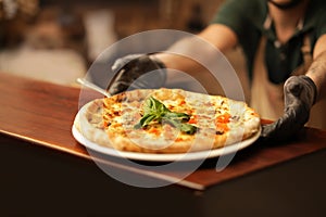 Man holding plate with oven baked pizza on table