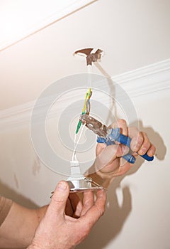 Man is holding pliers in his hands. Electrical insulator for light bulb. Adhesive tape for maintenance repair works in the flat.